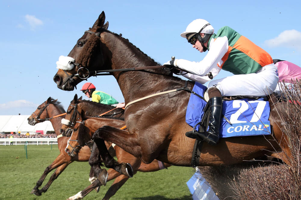 Steeplechase horses jumping a fence at Bangor-on-Dee Racecourse, illustrating National Hunt jump racing