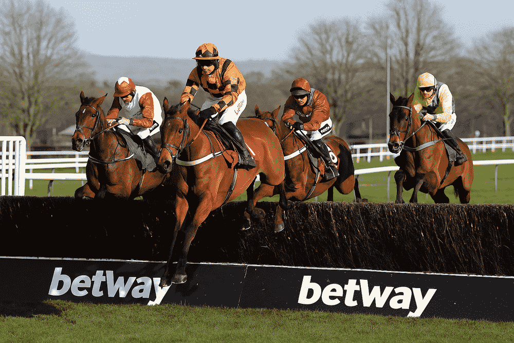 Four jockeys jumping a fence during a National Hunt steeplechase race