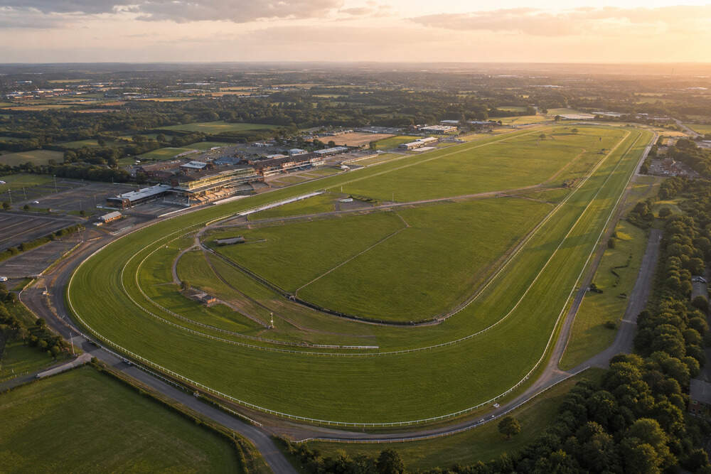 Aerial view of Doncaster Racecourse showing the full turf circuit, white rails, grandstands and surrounding grounds.