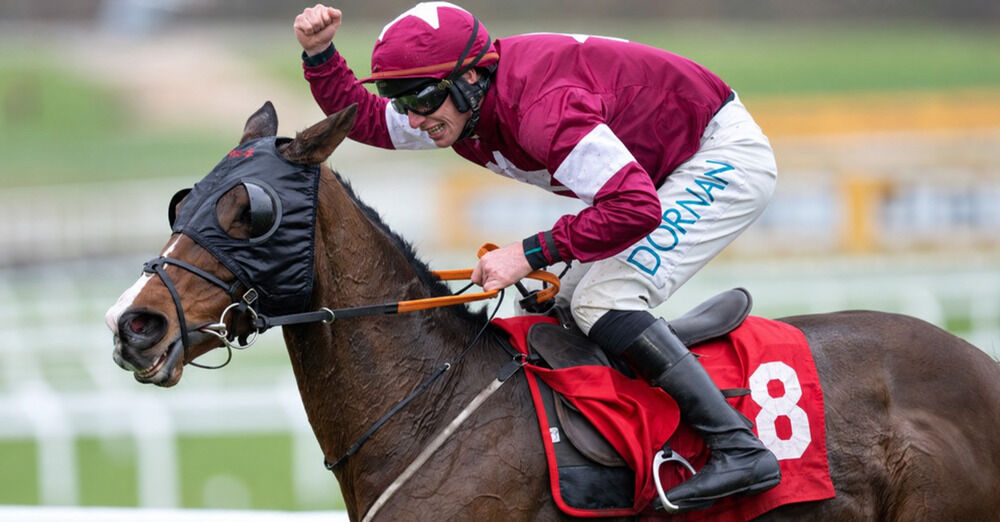 Jack Kennedy raises his fist in celebration while riding a National Hunt horse wearing number 8.