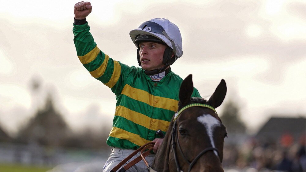 James Bowen raises his fist in celebration while riding a National Hunt racehorse.