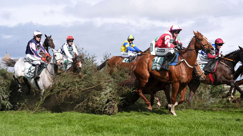 Grand National runners jumping a fence at Aintree Racecourse